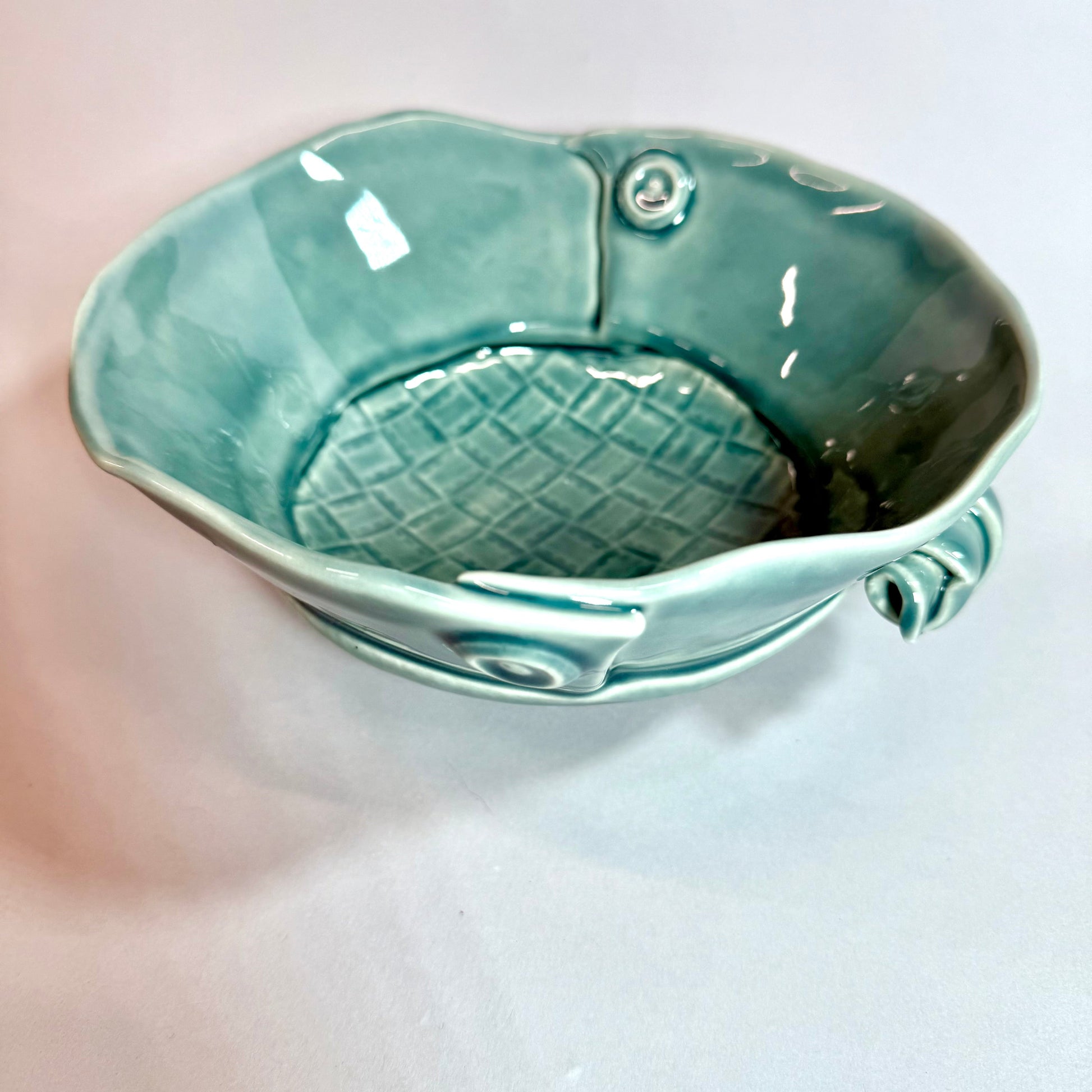 Turquoise ceramic bowl with woven center pattern and button-like side detail
